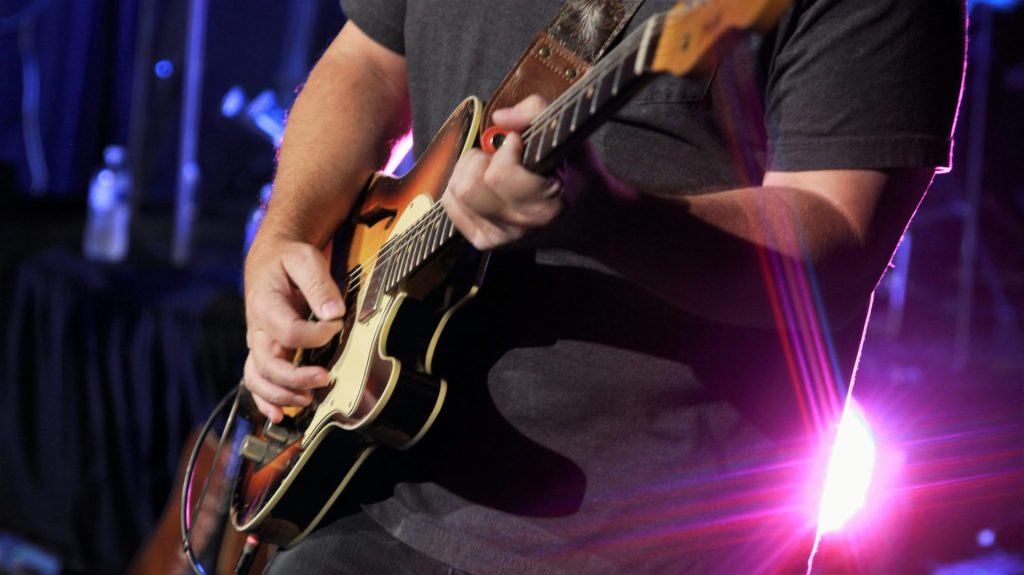 man in black t-shirt playing black and white electric guitar