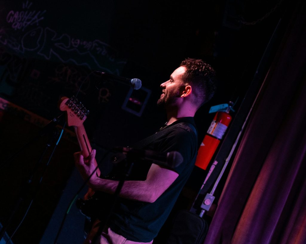A man standing on a stage with a guitar
